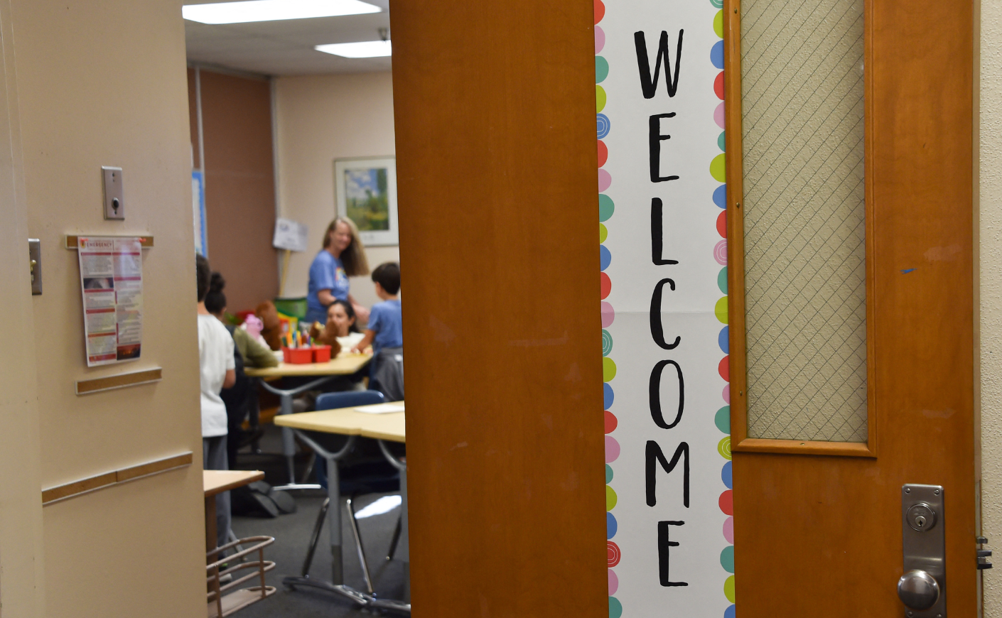 A peek into a classroom, where the door is ajar and there's a welcome banner on the door.