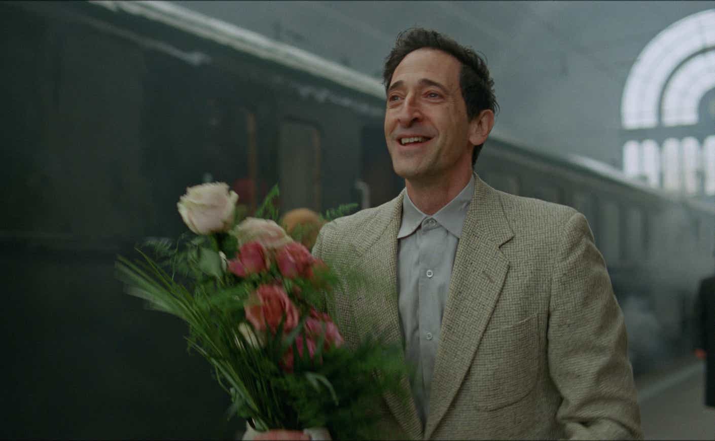 adrien brody holding flowers by a train in The Brutalist