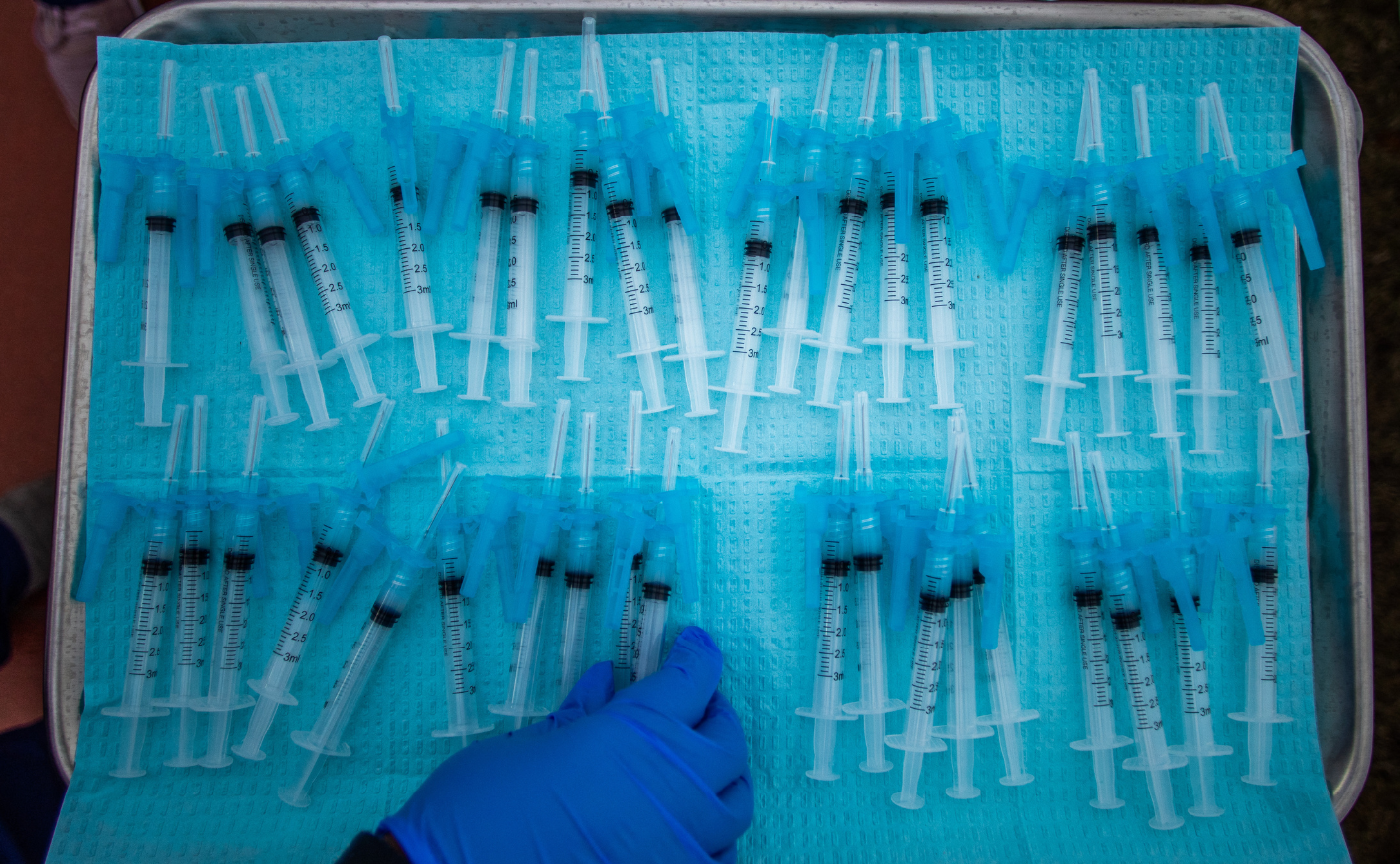 Doctor's hand reaching for a vaccine syringe