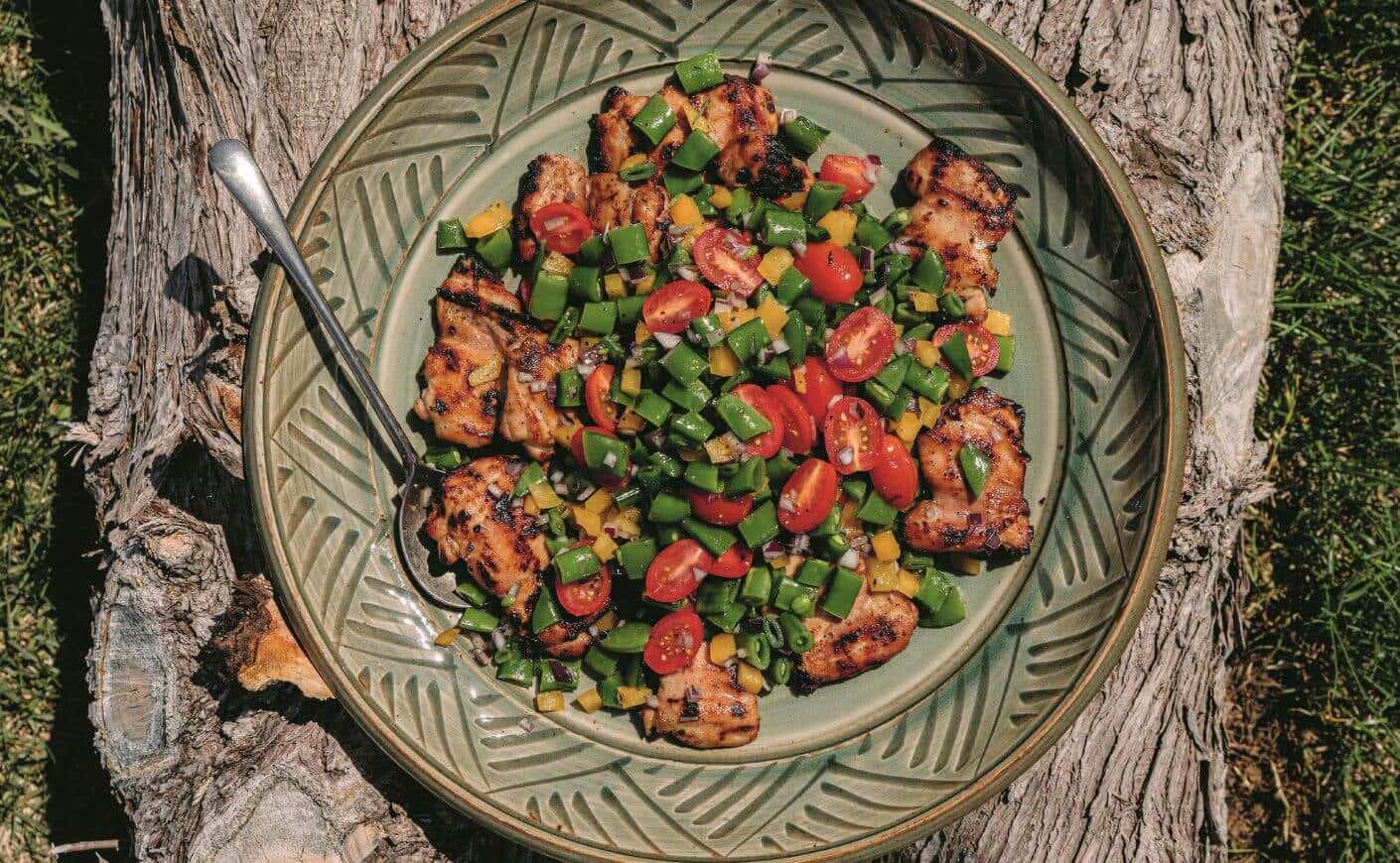 Dijon chicken thighs covered with snap pea and cherry tomato salad.