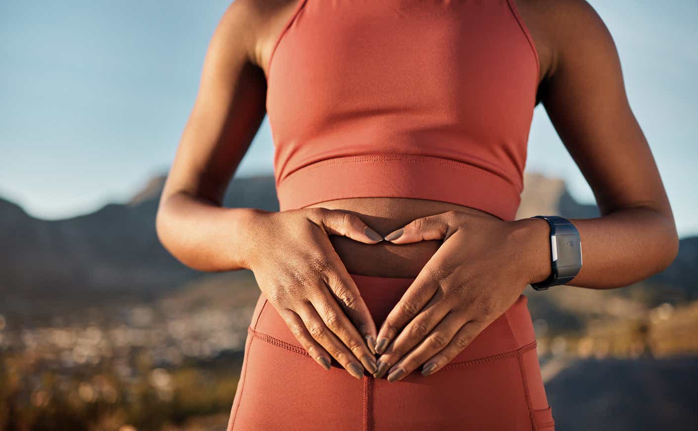 a woman places her hands in the shape of a heart over her stomach