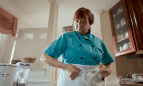 Chef Lisa Elsis stands in kitchen tying her apron