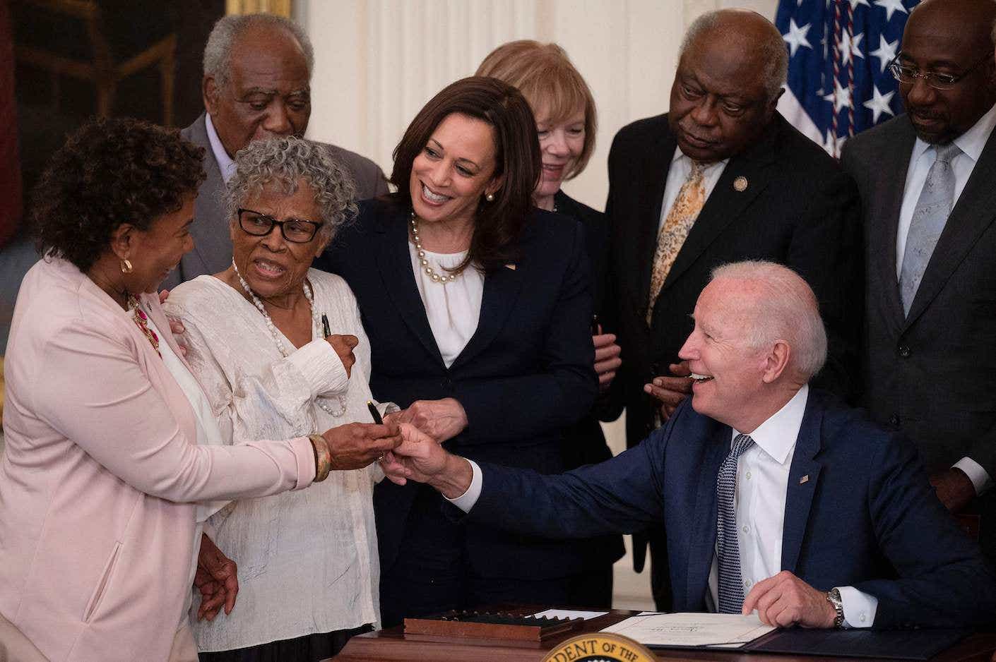 Opal Lee (2nd L), the activist known as the grandmother of Juneteenth, US Vice President Kamala Harris look on as US President Joe Biden gives a pen to US Congresswoman Barbara Lee (L) after signing the Juneteenth National Independence Day Act, in the East Room of the White House, June 17, 2021, in Washington. (Photo by JIM WATSON / AFP) (Photo by JIM WATSON/AFP via Getty Images)