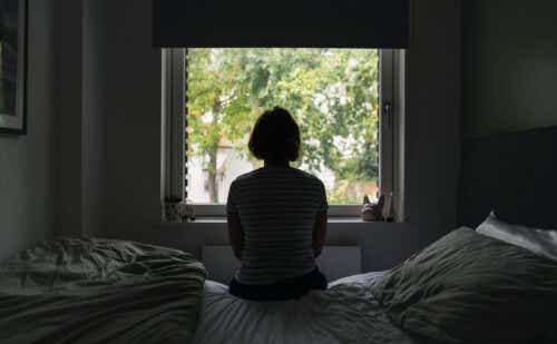 a woman in a dark room looking out a window
