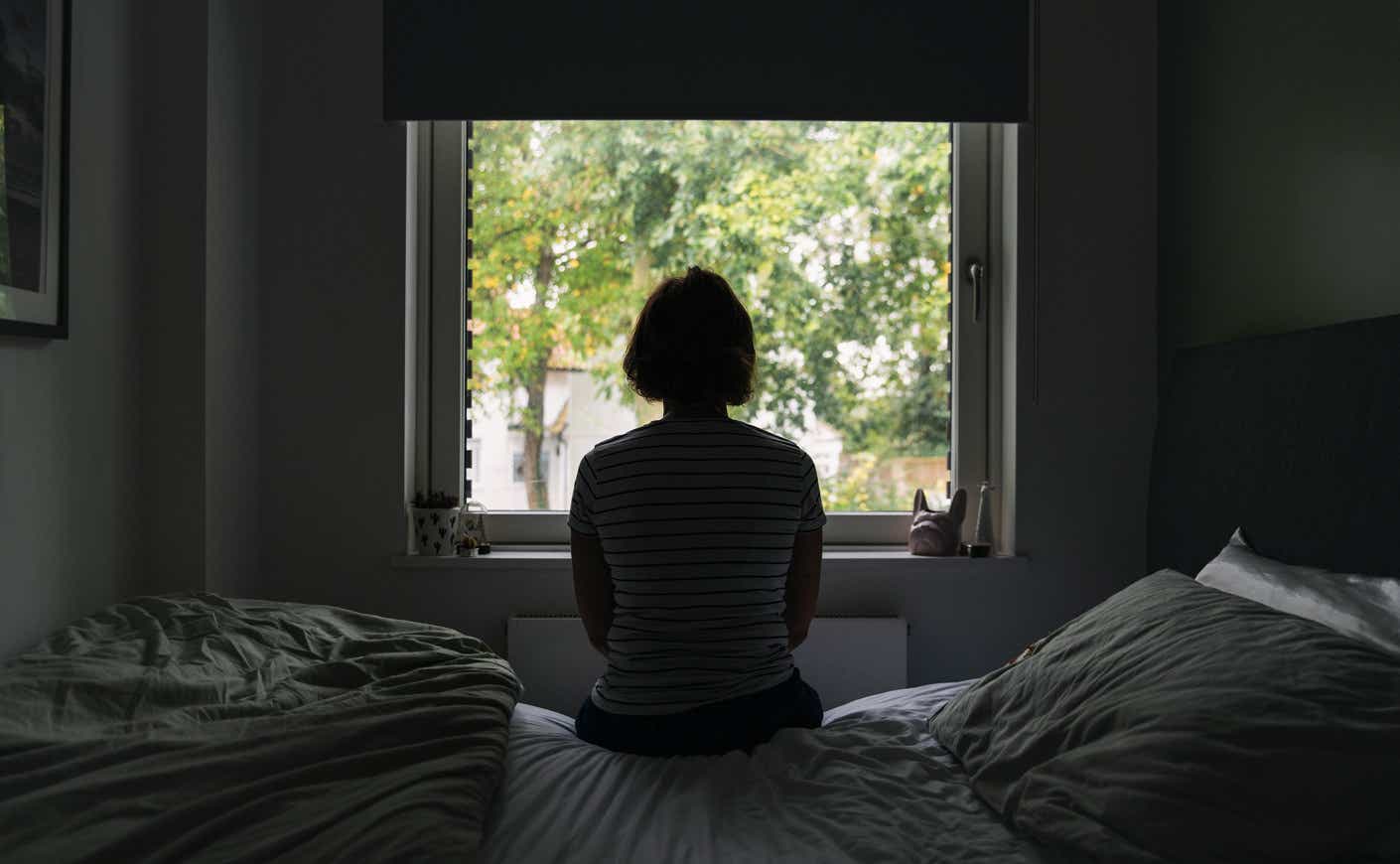 a woman in a dark room looking out a window