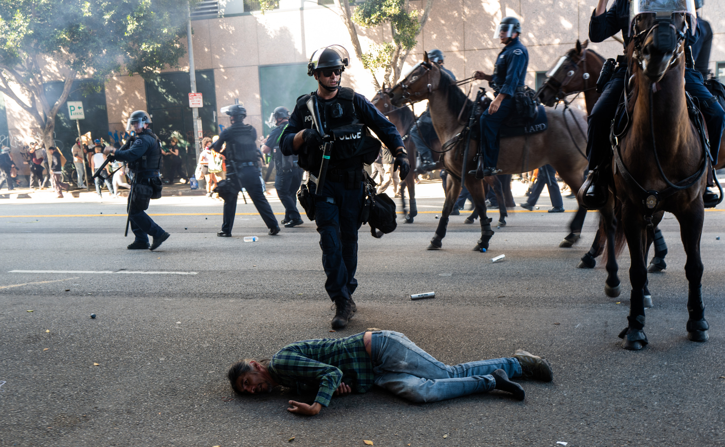 A protester lying on the concrete as cops in horseback approach him