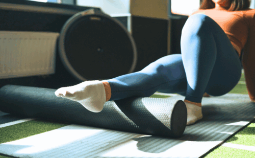 a woman rolling her calf on a foam roller