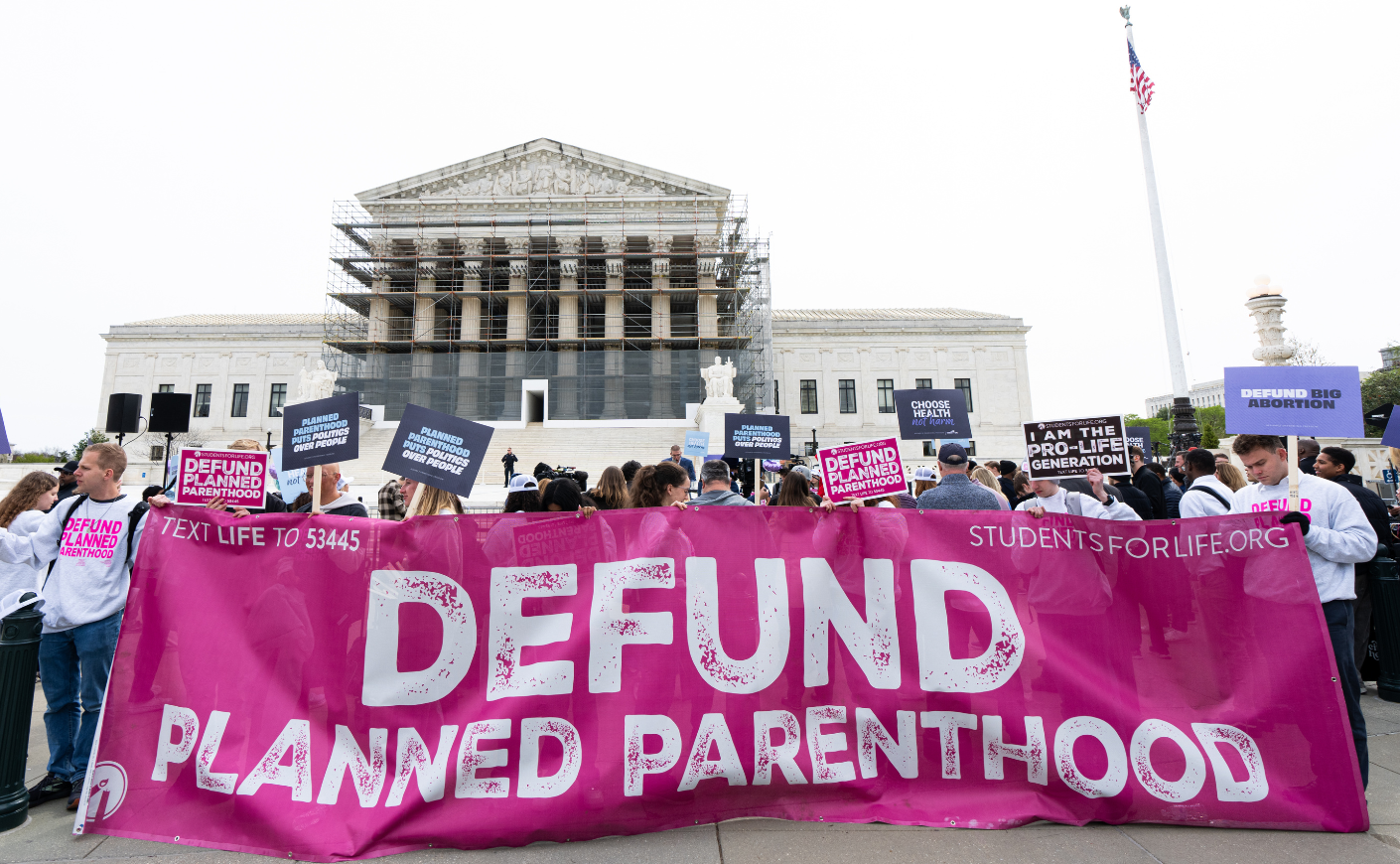 People hold a sign reading "Defund Planned Parenthood"