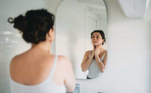 Woman looking in mirror with hands on her neck