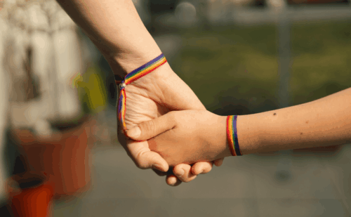 a parent and child holding hands with rainbow bracelets
