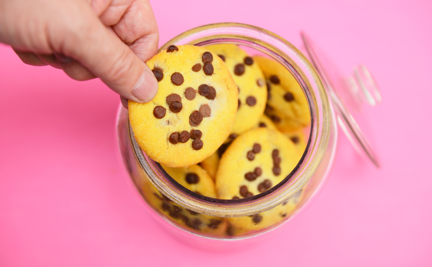 a person reaches into a jar for a cookie