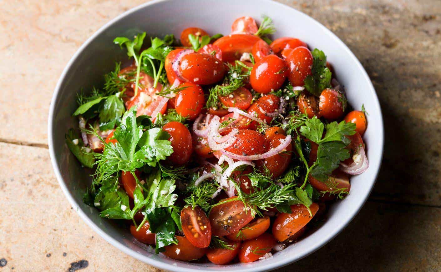 A bowl of grape tomato and dill salad.