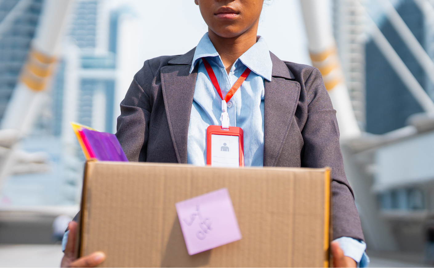 an office worker carries a cardboard box of her stuff