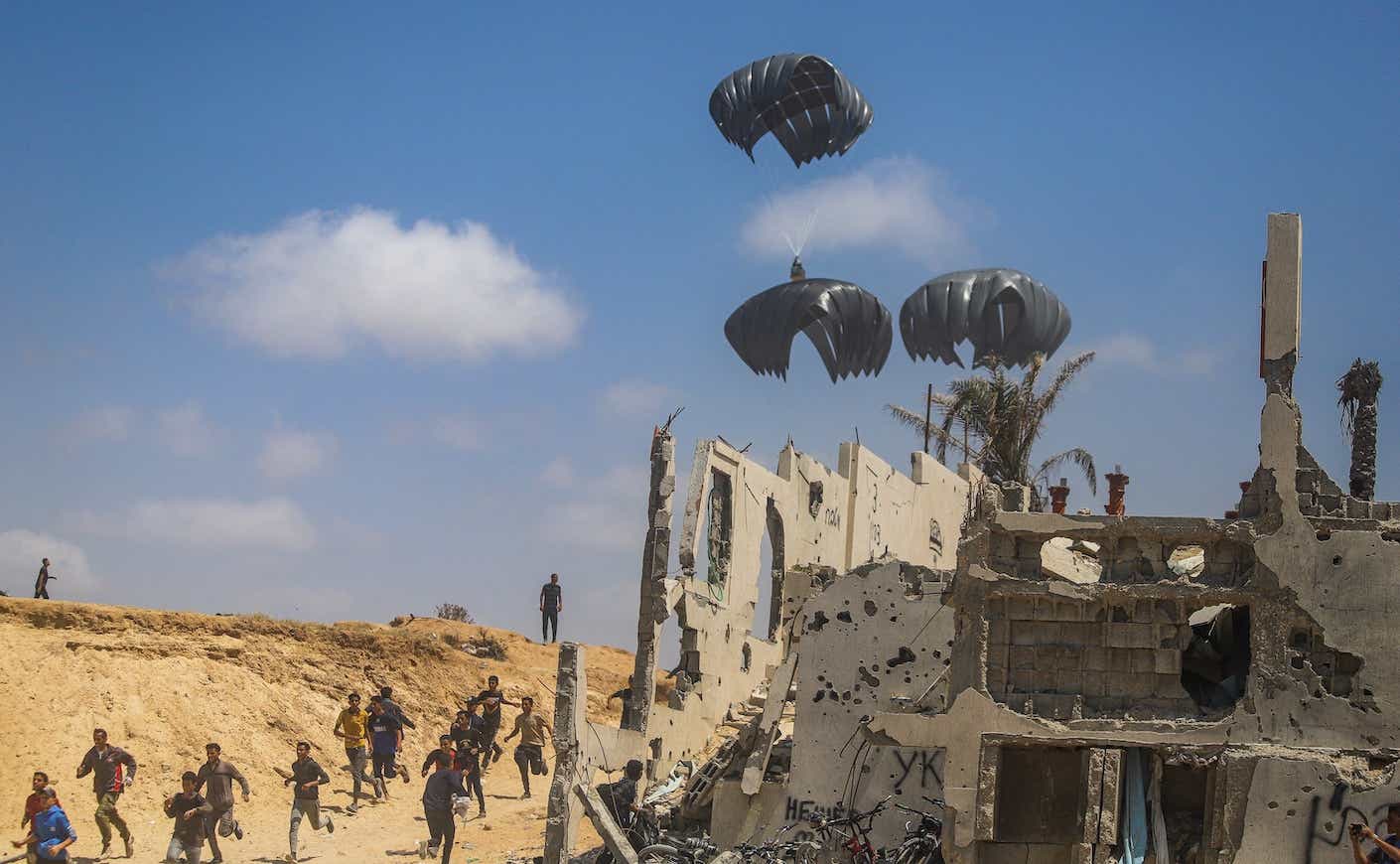 people rushing to collect aid from air drops over gaza