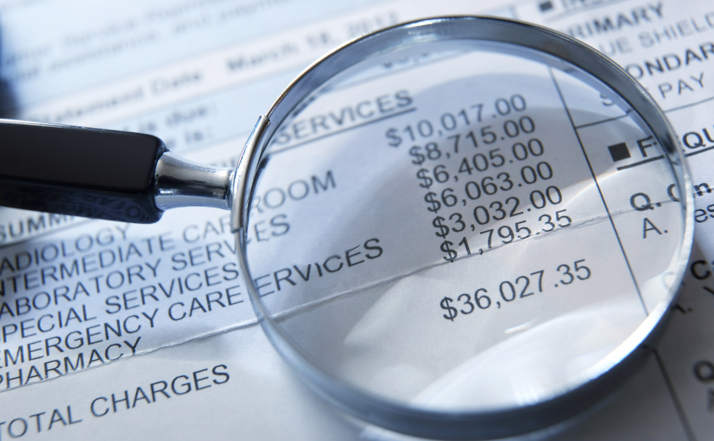 a magnifying glass on top of a medical bill