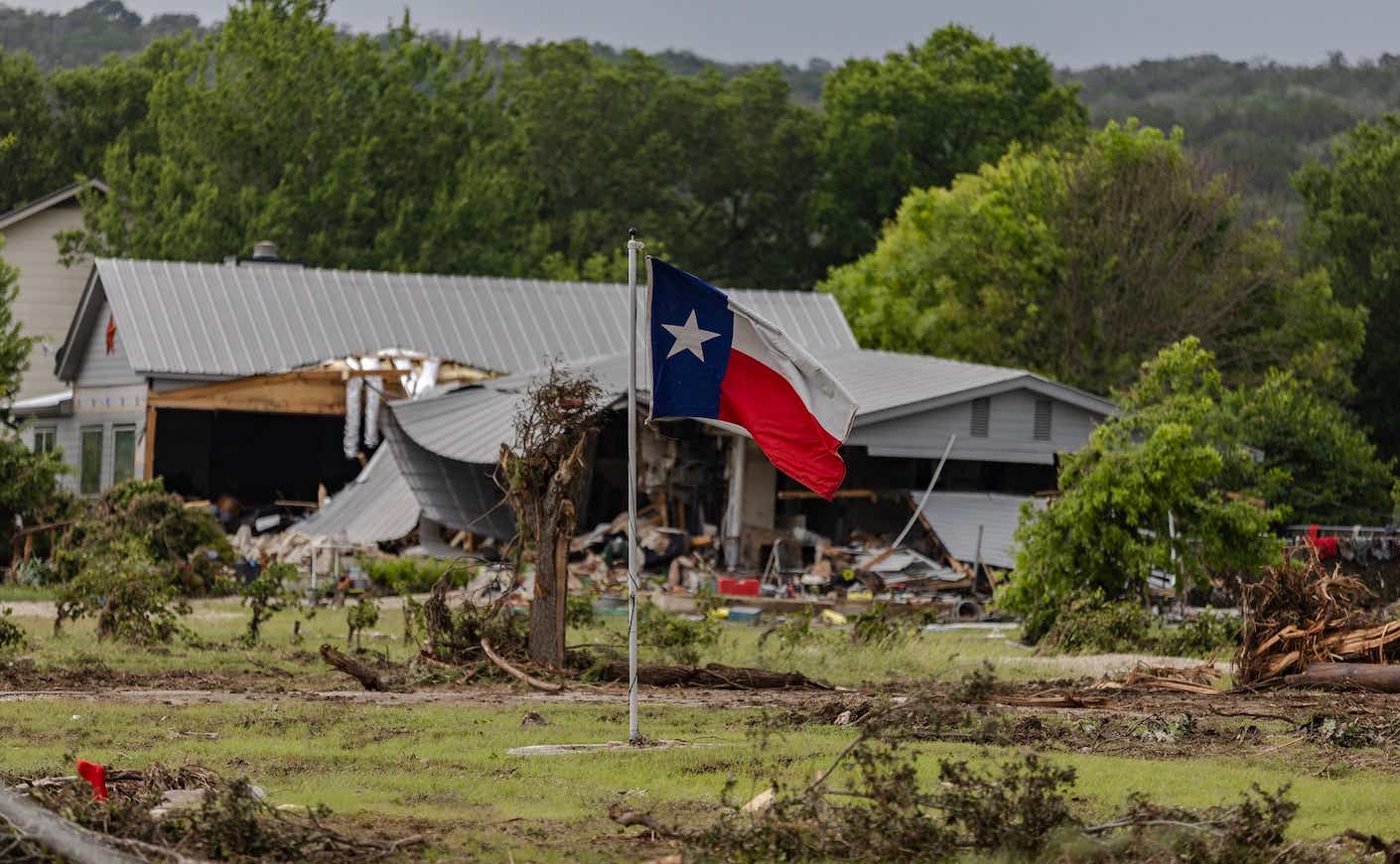 A Texas state flag flies in a yard filled with debris on July 6, 2025 in Hunt, Texas.