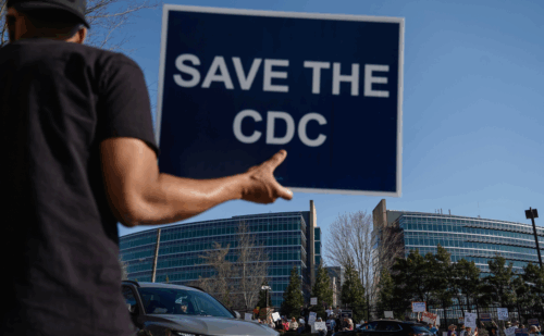 Man holds a sign reading "Save the CDC"