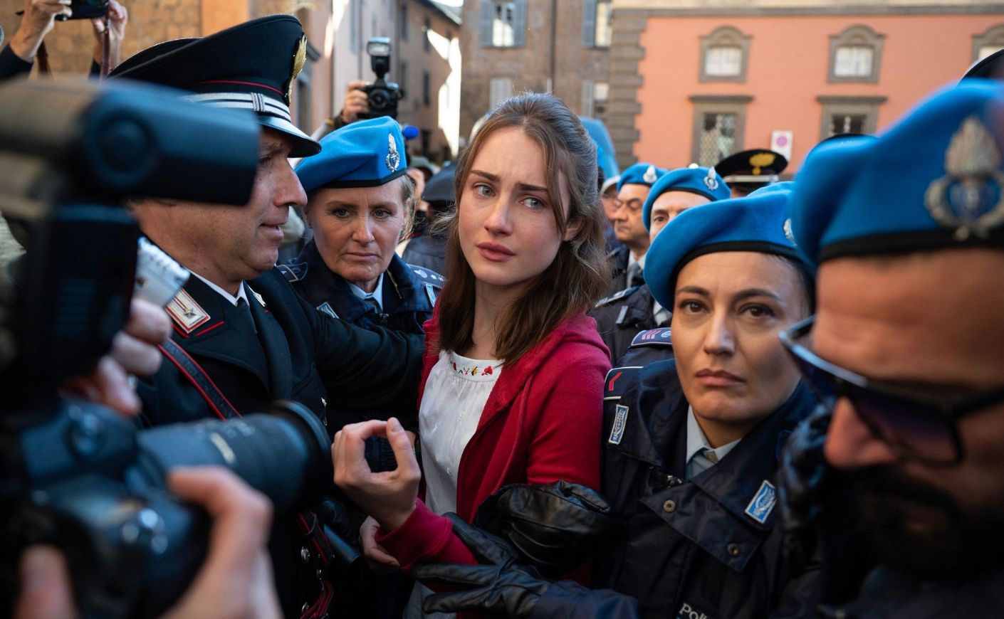 Grace Van Patten as Amanda Knox, surrounded by paparazzi and Italian carabinieri in blue hats