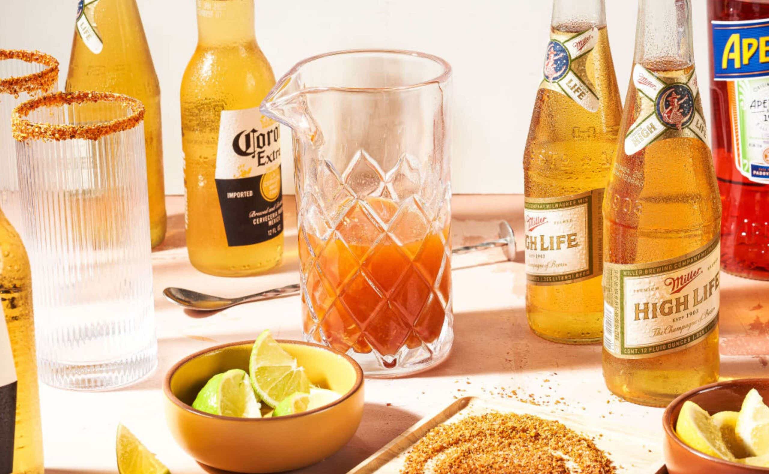 A spread of bottled beer, Aperol, and citrus slices on a table.