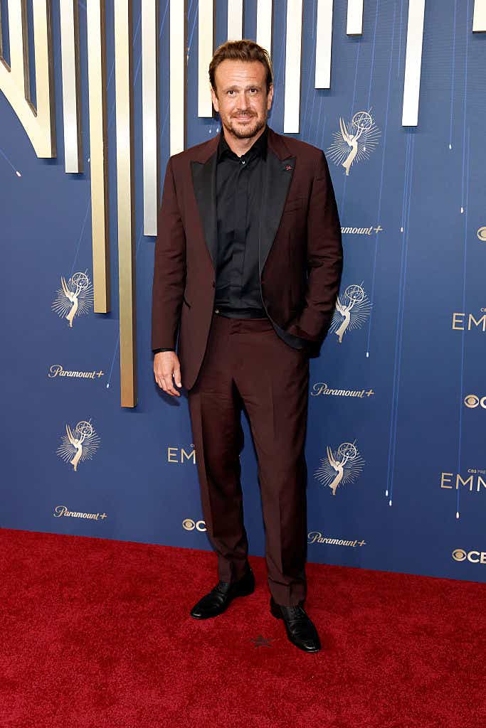 Jason Segel wears a burgundy tux with a black shirt underneath to the Emmys.