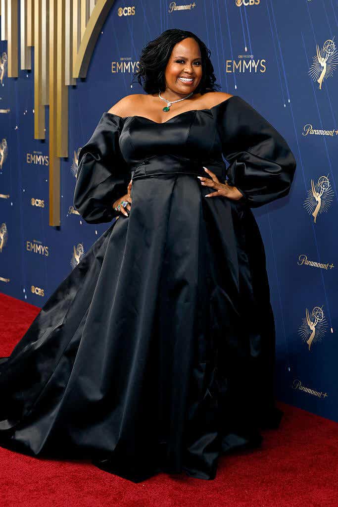 Natasha Rothwell wears a black gown with an off-the-shoulder top, long puffy sleeves, and a voluminous skirt to the Emmys.