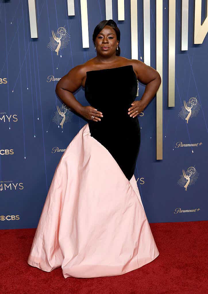 Uzo Aduba wears a gown with a black strapless top featuring an architectural square neckline and an asymmetrical puffy light pink skirt.