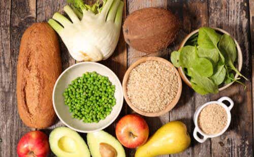 A pile of fiber-rich foods, including loaf of bread, avocados, and apples