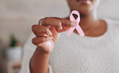 A person holding a pink breast cancer ribbon