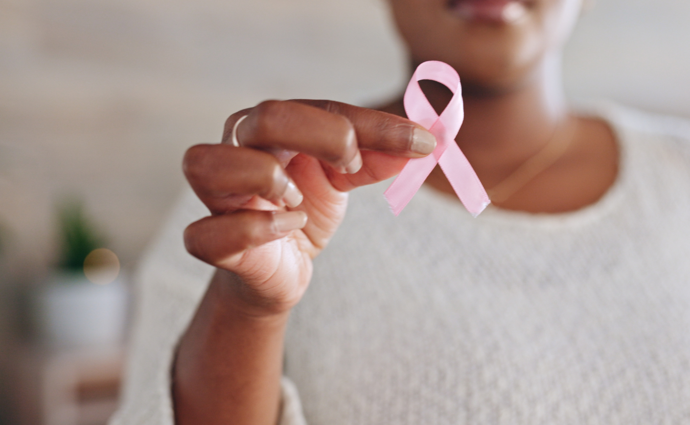 A person holding a pink breast cancer ribbon