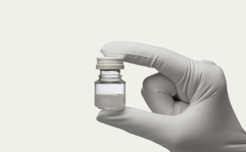 gloved hand holding vial