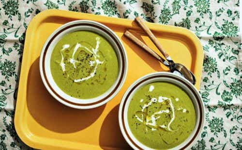 Two bowls of broccolini and gouda soup on a tray.