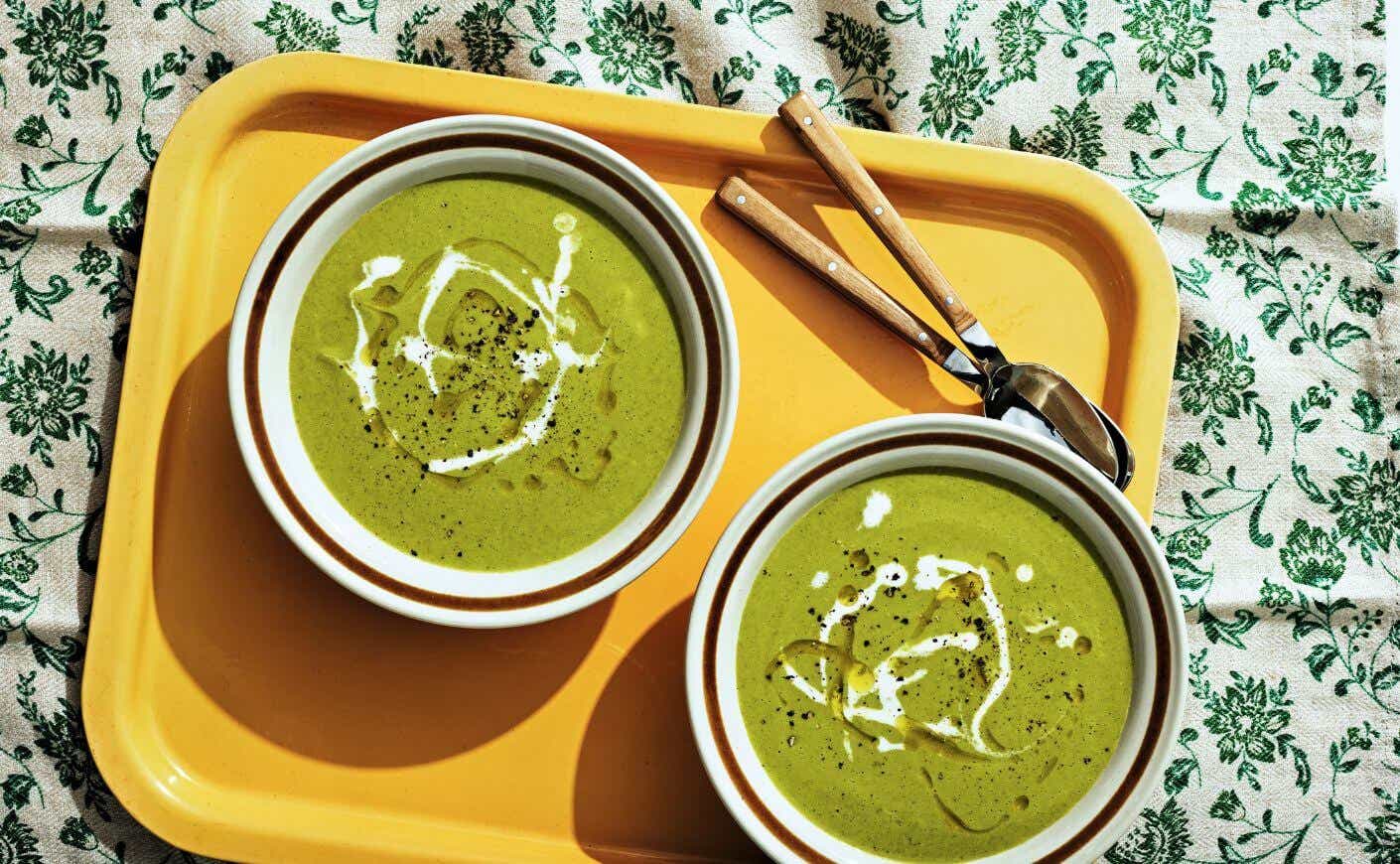 Two bowls of broccolini and gouda soup on a tray.