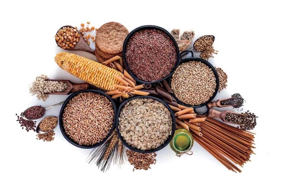 Four bowls of grain surrounded by corn, whole wheat pasta