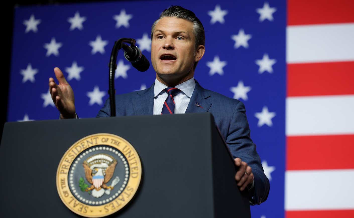 pete hegseth speaking at a podium in front of an american flag