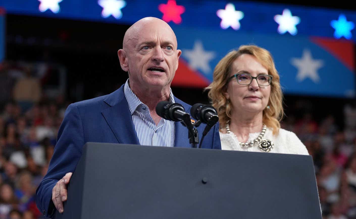 mark kelly and his wife gabby giffords speaking on stage