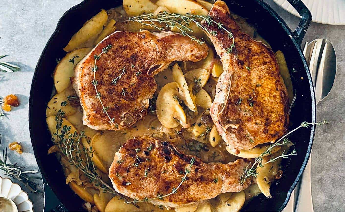 Pork chops and apples in a cast iron pan.