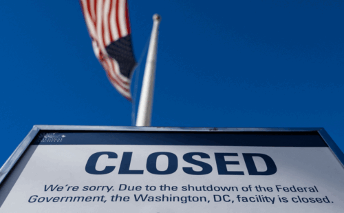 A sign beneath a flagpole that says CLOSED: We're sorry. Due to the shutdown of the Federal Government, the Washington, D.C. facility is closed.