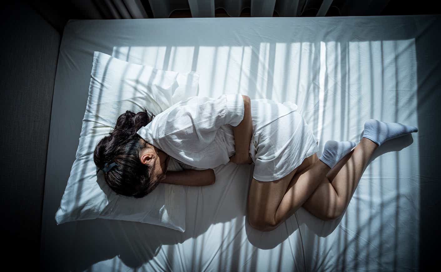 woman in the fetal position in bed