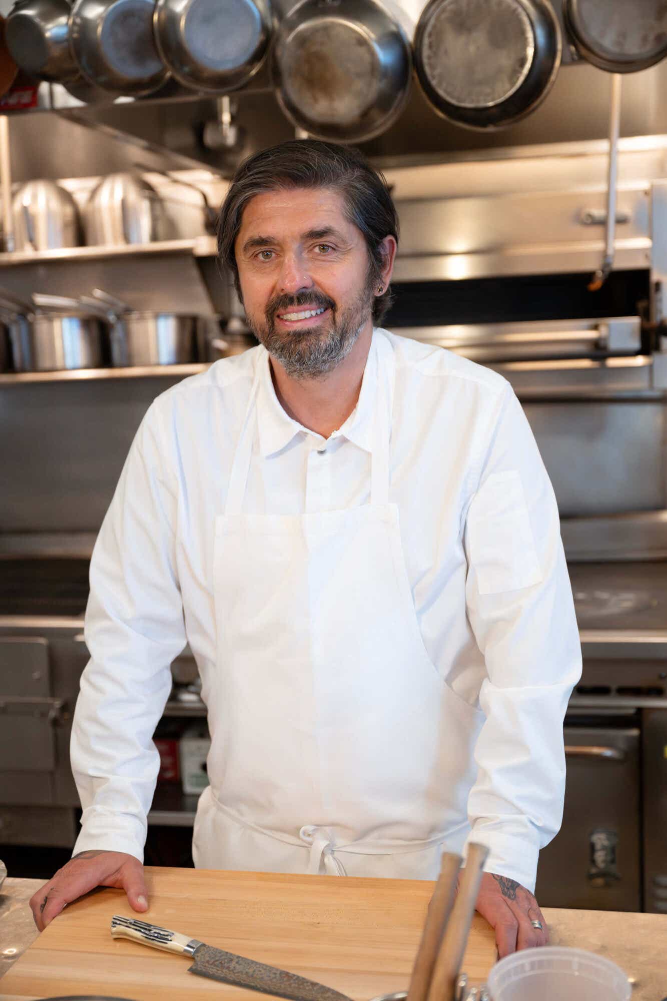 Chef Ludo stands at his kitchen in front of a cutting board and knife