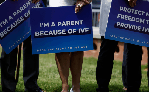 Person holding a sign reading "I'm a parent because of IVF"