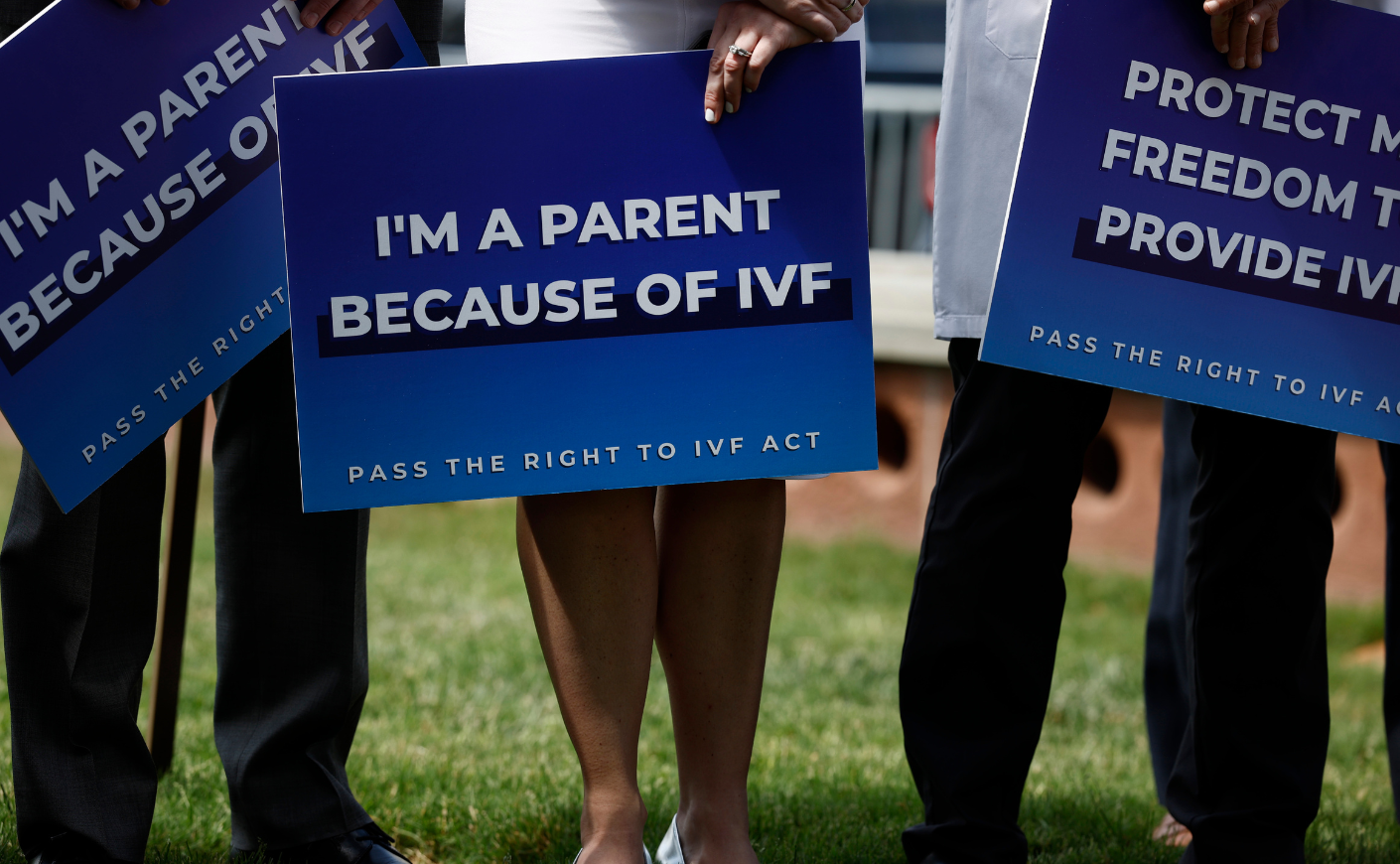 Person holding a sign reading "I'm a parent because of IVF"