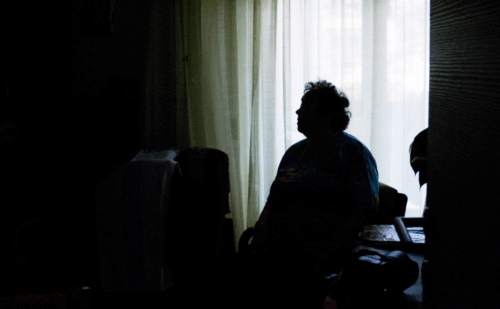 Silhouette of an elderly woman sitting alone in a room