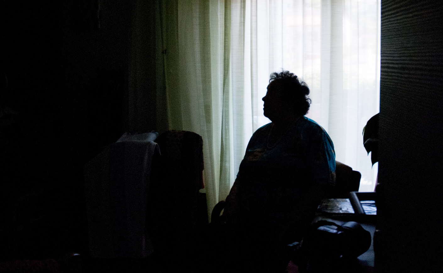 Silhouette of an elderly woman sitting alone in a room