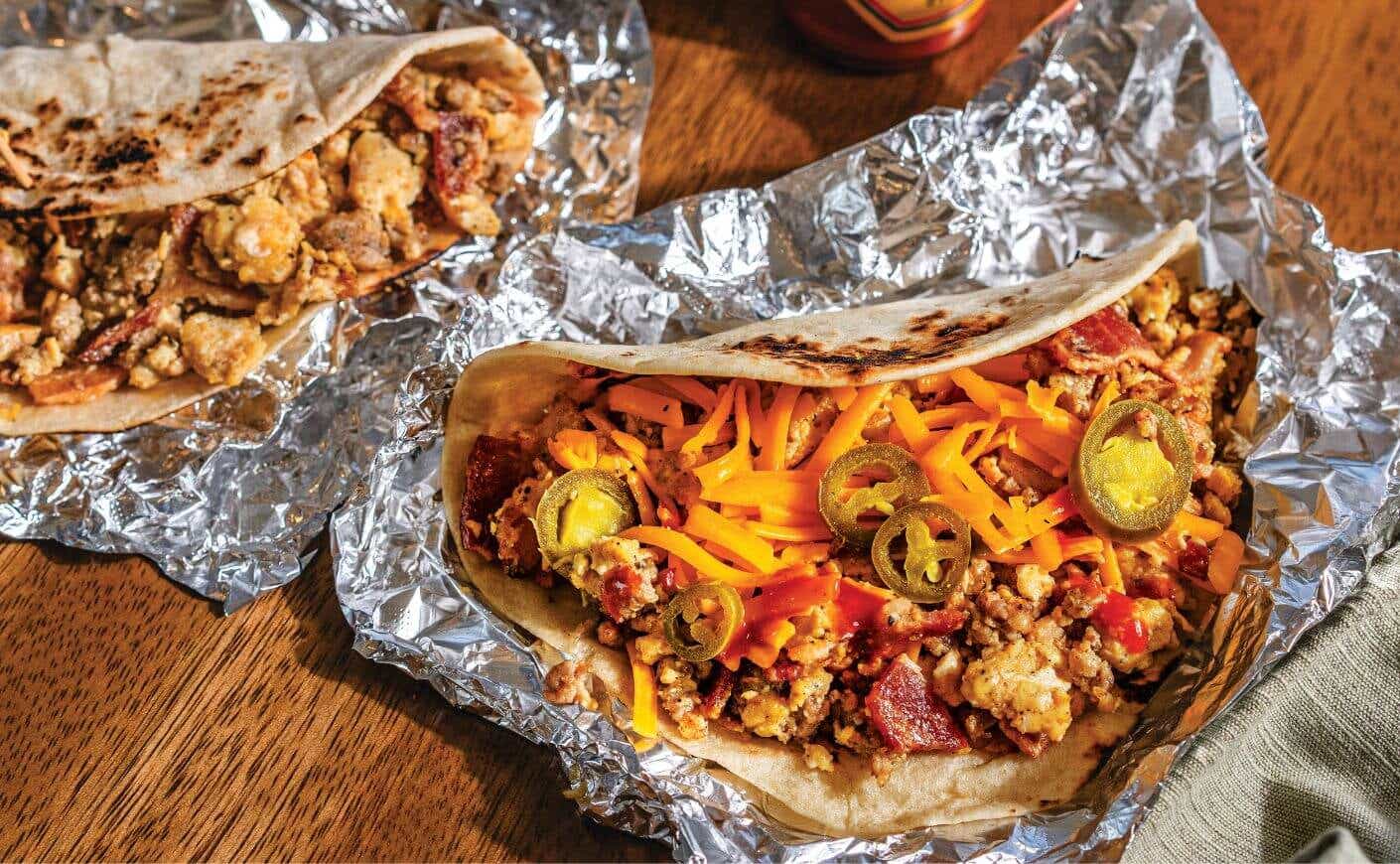 Two breakfast burritos in foil.