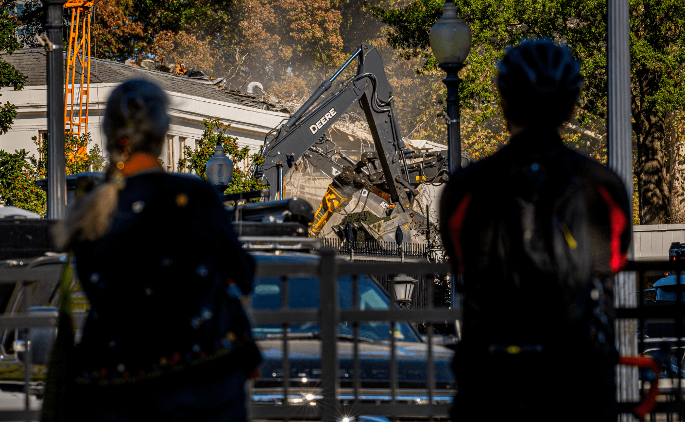 Pedestrians stop to watch the facade of the East Wing of the White House being demolished by work crews on October 21, 2025, in Washington, D.C. 