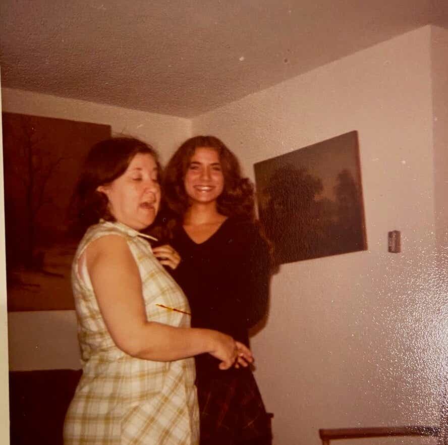 two women standing, one smiling, the other talking