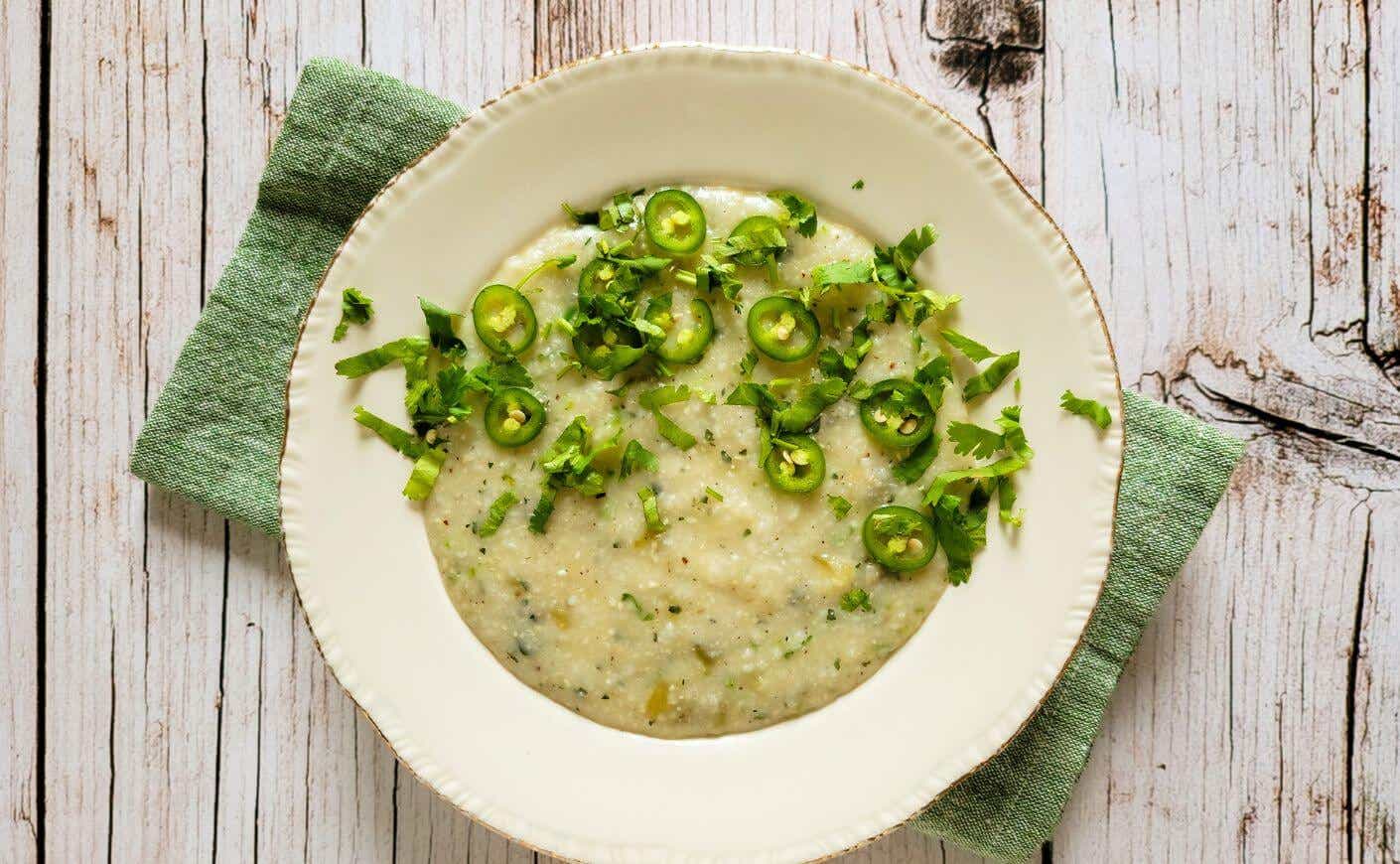 A bowl of grits garnished with green chiles.