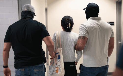 woman being detained by ice agents