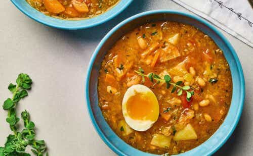 A bowl of vegetable soup topped with half of a jammy egg.