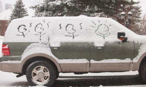 Car with snow on windows, drawings of stick figure family drawn into snow